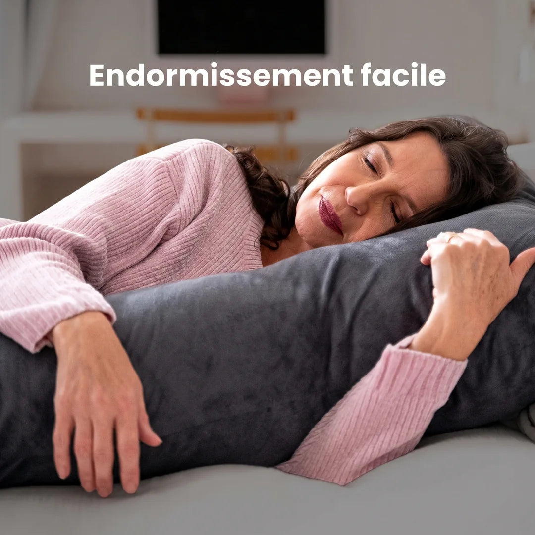 Une femme s'endort, enveloppée par un long coussin en velours anthracite : « Endormissement facile »