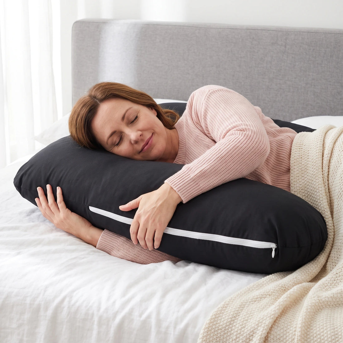Une femme sereine, les yeux fermés, serre la branche de son coussin en U à housse de coton noir